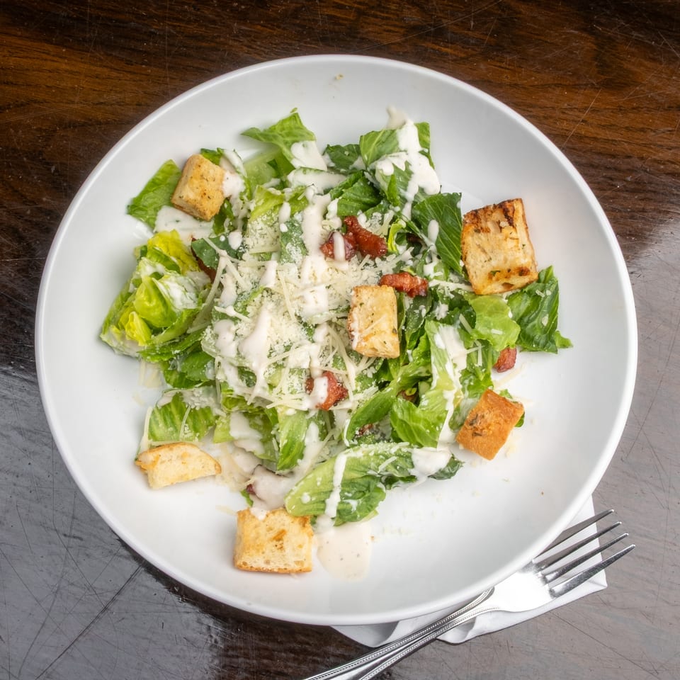 Caesar salad with romaine lettuce, croutons, bacon bits, parmesan cheese, and creamy dressing.