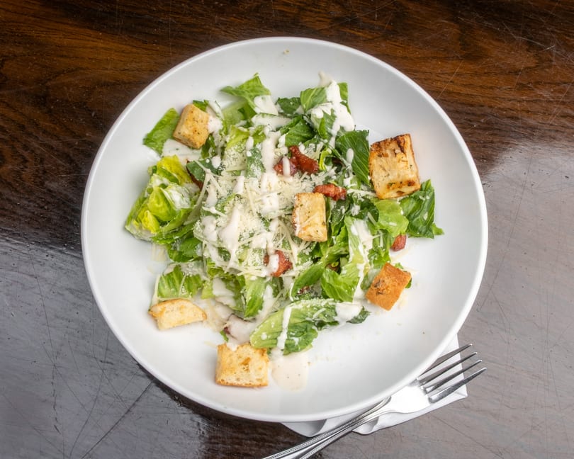 Caesar salad with romaine lettuce, croutons, bacon bits, parmesan cheese, and creamy dressing.